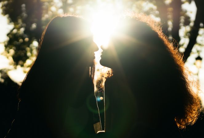 silhouette of two women kissing in the sunlight