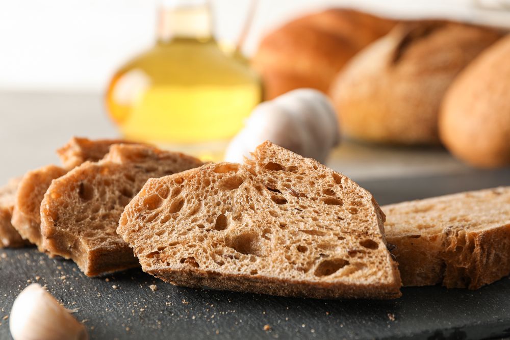 Composition with bakery products, garlic and olive oil on grey background, closeup and space for text