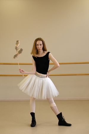 Ballerina in shoes and tutu, holding ballet slippers