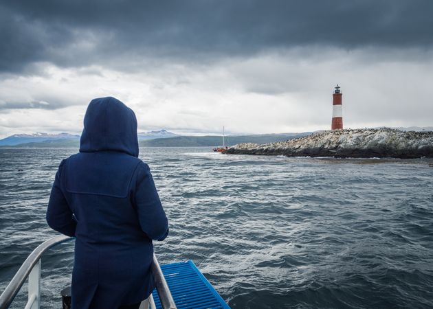 Anonymous person looking at lighthouse from ship