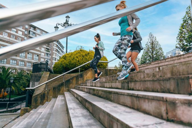 Fit females training running down stairs in town