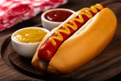 Close up of hot dog with mustard on wooden board