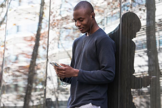 Black man listening to music in earphones on smartphone