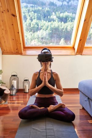 Concentrated woman in VR glasses practicing Lotus asana and nama