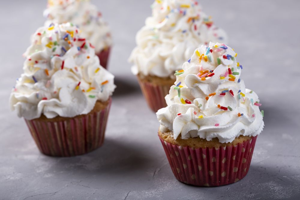 Tasty party cupcakes on the table. Cupcakes with whipped cream.