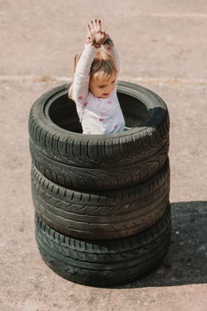 Little girl standing in stack of tires