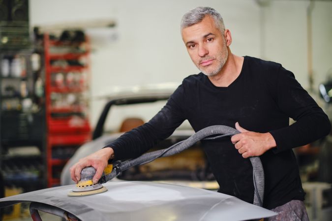 Mechanic grinding paint from car detail