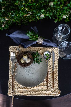 Top view of elegant Easter table setting with pussy willow and small bird's nest on grey plate