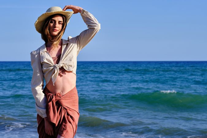 A fashion model with a hat at the beach before sunset