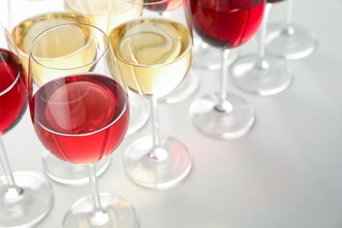Glasses with different wine on plain background, close up