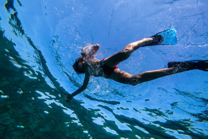 Preteen boy swimming underwater in flippers and snorkeling mask