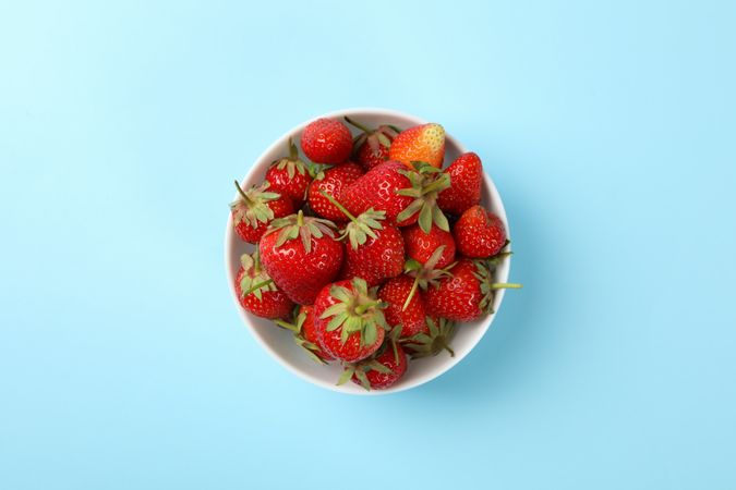 Bowl with tasty strawberry on blue background. Summer berry