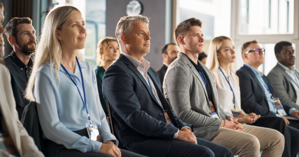 Male CEO Sitting in a Bright Crowded Auditorium at a Technology Conference. Confident Man Watching Interesting Keynote Presentation. Specialist Inspired by Latest Technological Advances, Developments.