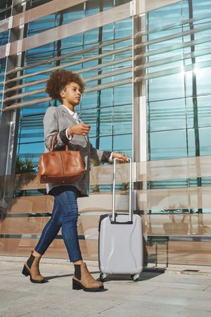 Black woman with suitcase talking on smartphone