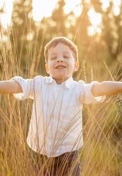Kid in field playing with spikes at summer sunset