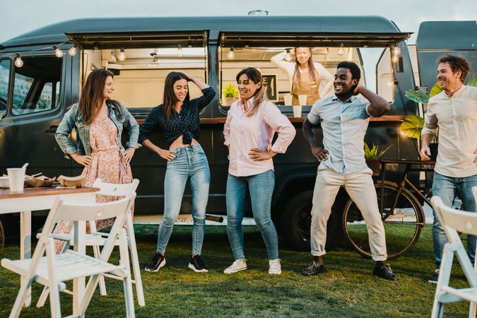 Multiracial friends dancing near food truck in park