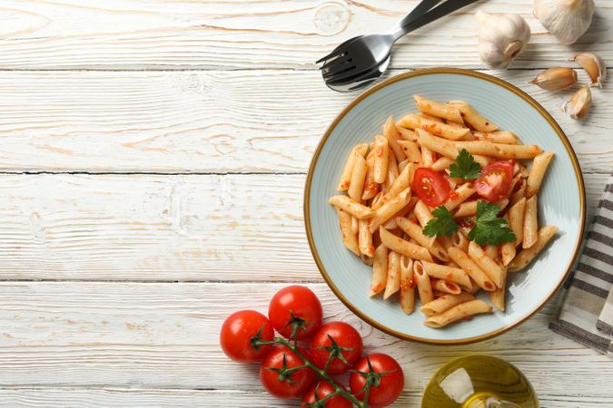 Composition with plate of tasty pasta and ingredients for cooking on wooden background