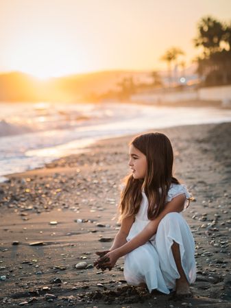 Adorable girl playing with sand on beach