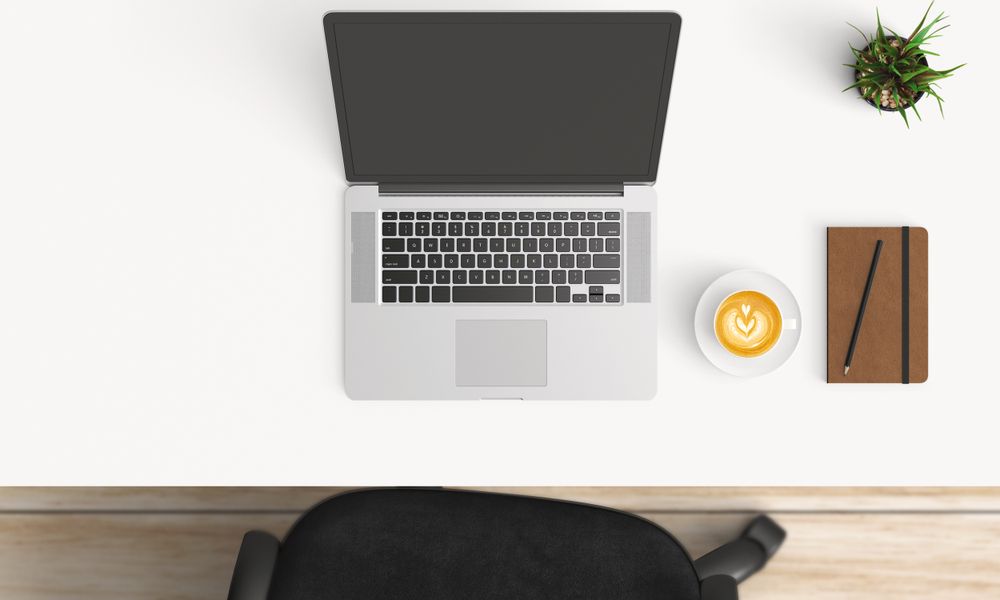 Modern workplace with laptop, coffee cup and notebook copy space on table background. Top view. Flat lay style.