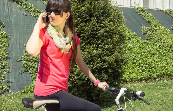 Sportive woman with fixie bike calling by phone