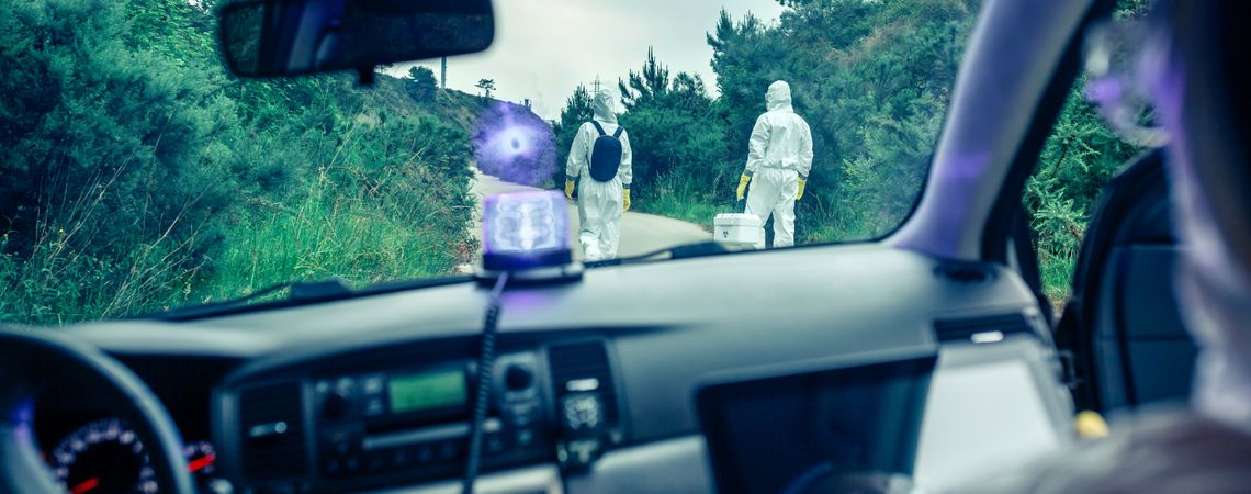 View from inside the car of people in bacteriological protection suits doing research