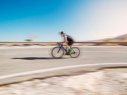 healthy man riding a bicycle on a mountain road in a sunny day