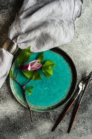 Floral scene with magnolia blooming on teal plate with napkin