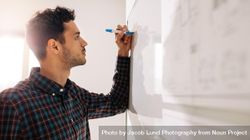Male professional writing on dry erase board using a marker pen 0gVM8b