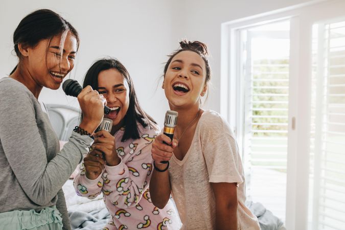Young women enjoying singing karaoke during a sleepover