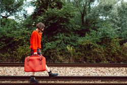 Woman with suitcase walking on railroad ties