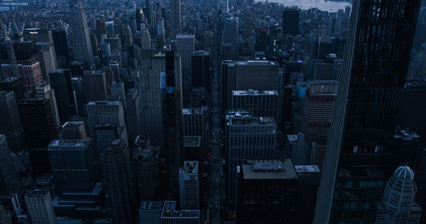 Dark Aerial Evening Photo of New York City with Straight Busy Streets with Cars and Yellow Taxi Vehicles. Lowered Helicopter View of Office Buildings and Skyscrapers in a Big Urban Center