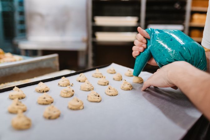 Crop baker squeezing dough on tray