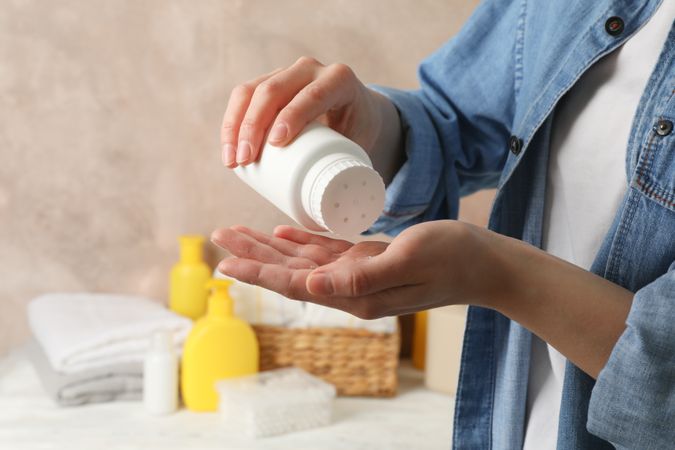 Mom applying talc powder from plastic tube. Baby hygiene