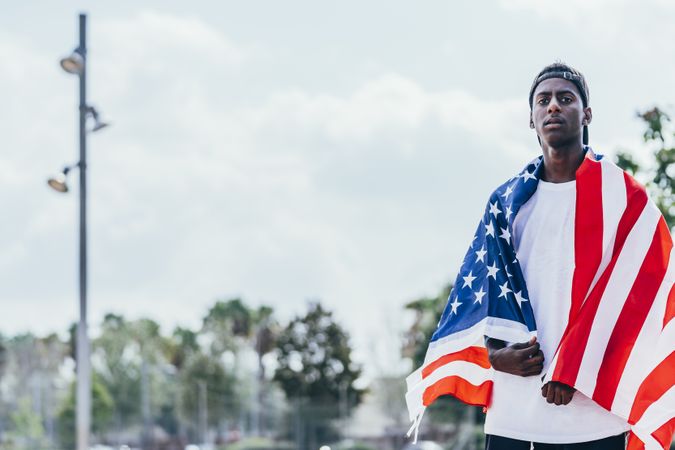 Black man wrapping American Flag outside