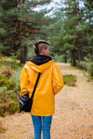 Person in yellow raincoat walking in forest