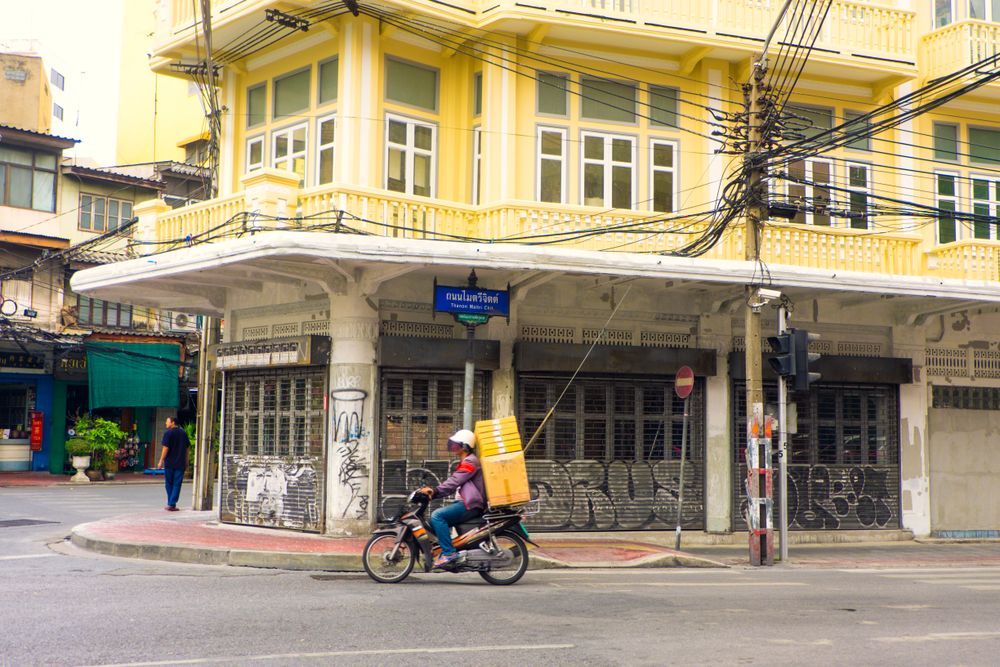 Side view of man riding a bike on road near residential building in Vietnam