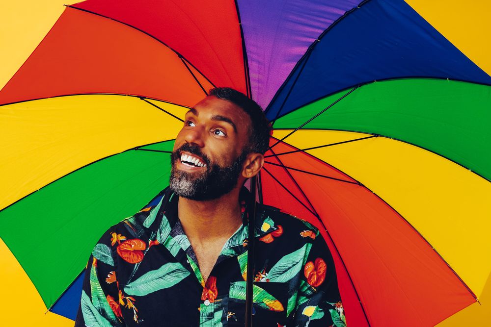 Smiling man looking up from under colorful umbrella