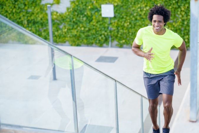 Happy man in neon T-shirt running up steps outside