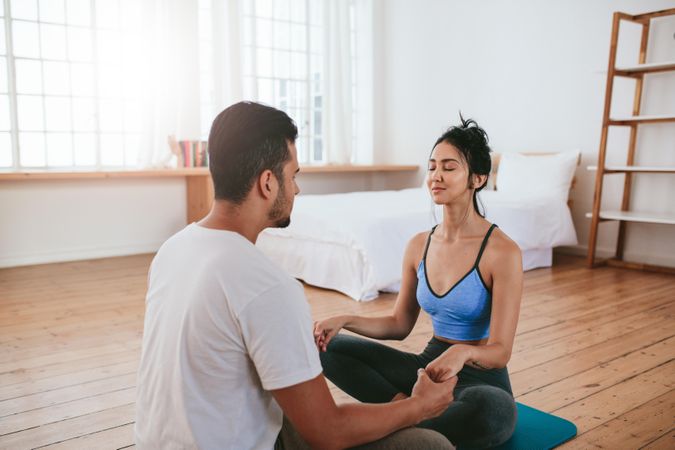 Young man and woman doing yoga together at home