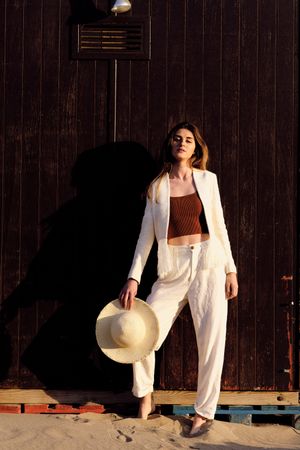 A long hair fashion model with a hat at the beach with a dark background