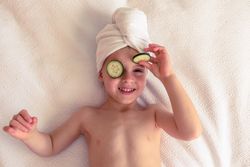 Cheerful boy with cucumber slices on eyes