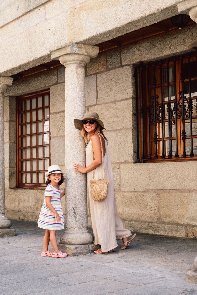 Mother and daughter walking in street along ancient building