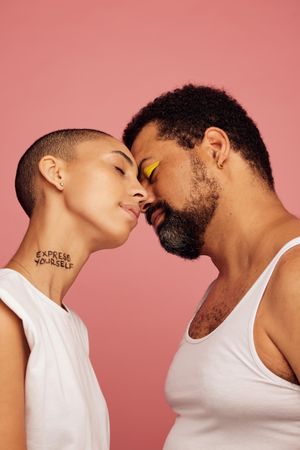 Man in make up and woman with shaved head with their faces close