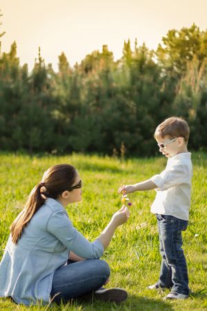 Son giving a bouquet of flowers to his pregnant mother in a field