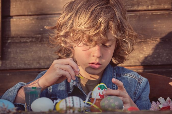 Concentrated boy with Easter eggs