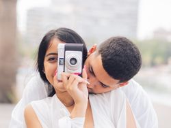 Woman taking photo and sitting with man on bench