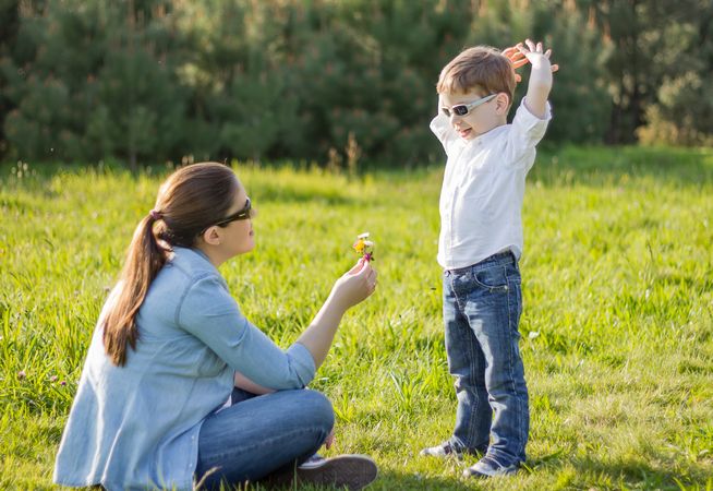 Son giving a bouquet of flowers to his pregnant mother in a field