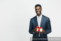 Professional Black man smiling while holding a wrapped present 4OB775