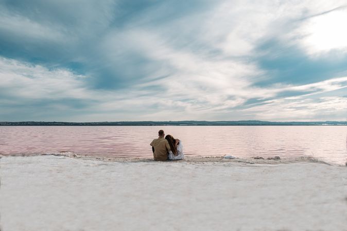 adorable couple sitting on an amazing beach with pink water