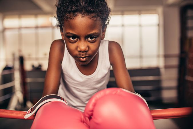 Girl wearing boxing gloves standing inside a boxing ring